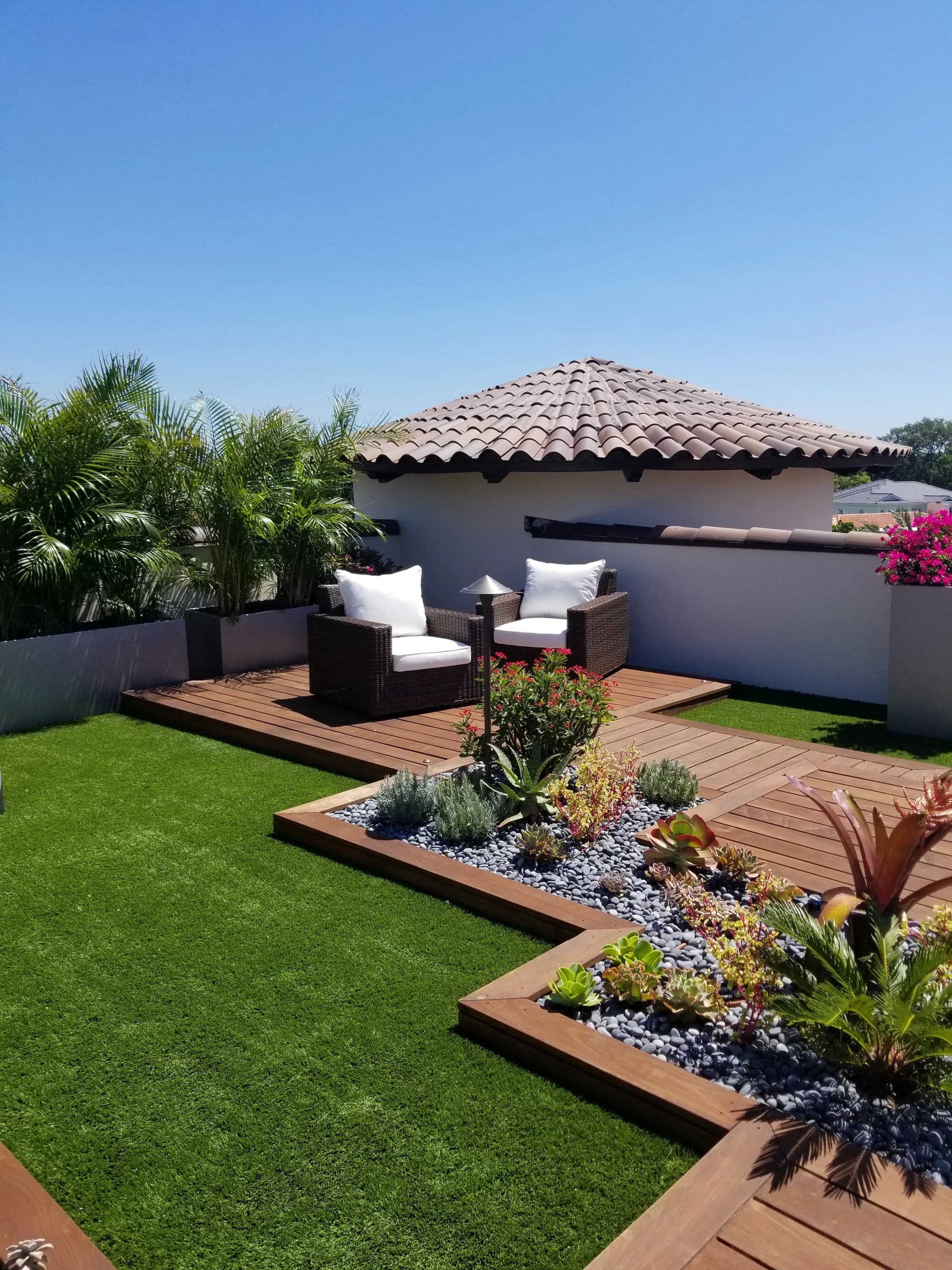 Luxury backyard with white stucco cabana, wooden deck, manicured lawn, and designer outdoor seating in St Petersburg residential community.