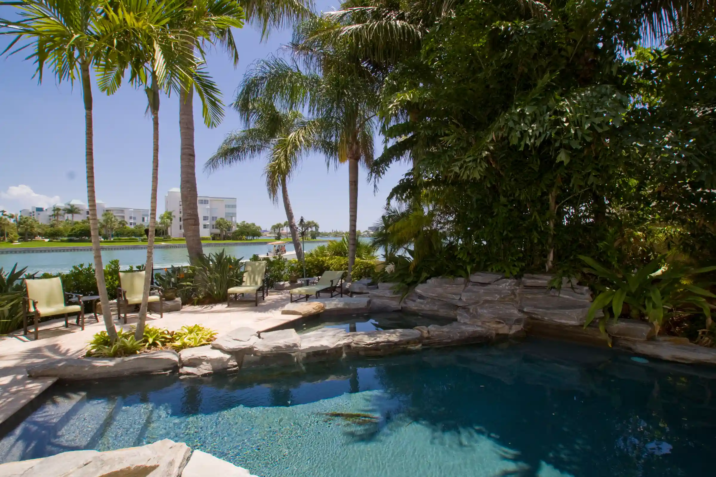Luxury pool with natural stone features, palm trees, and waterfront views in St Petersburg residential community