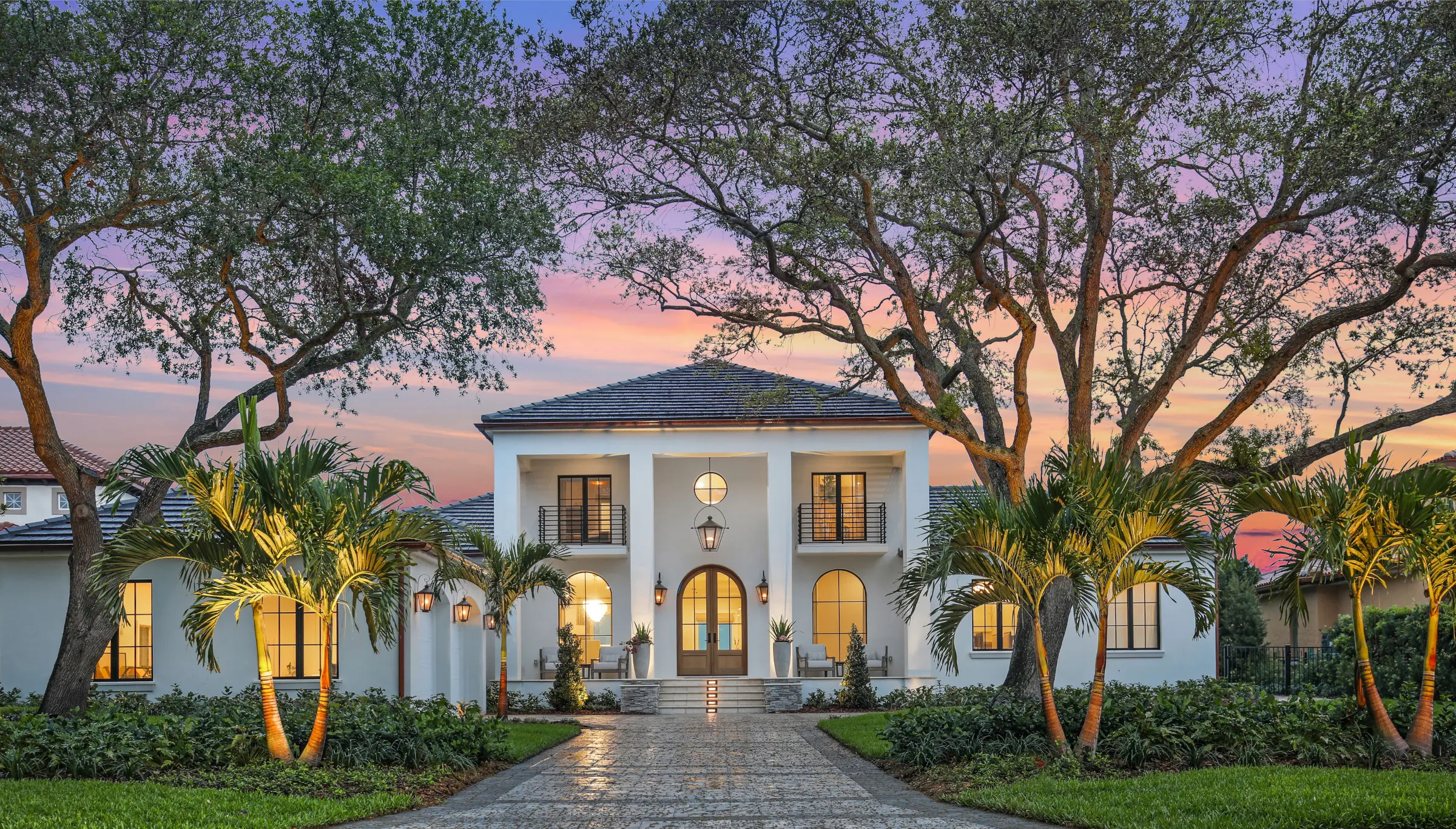 Luxury white contemporary home with palm trees and mature oaks at dusk, featuring landscape architecture and elegant outdoor design in St Petersburg FL.