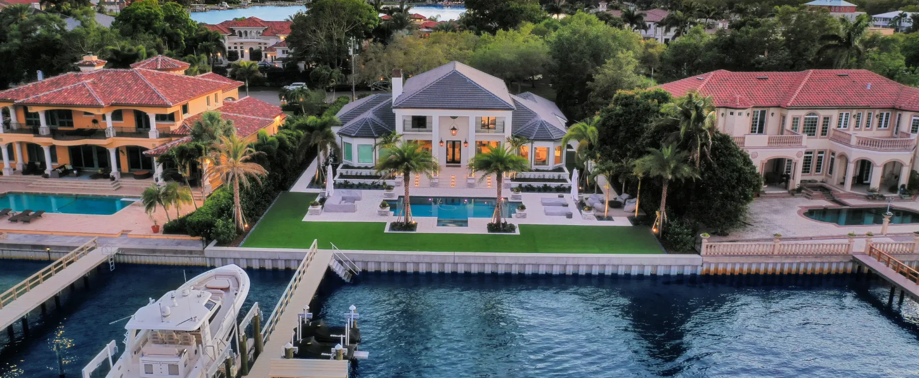 Luxury waterfront home with white colonial architecture, resort-style pool, boat dock, and manicured landscape in St Petersburg residential community.