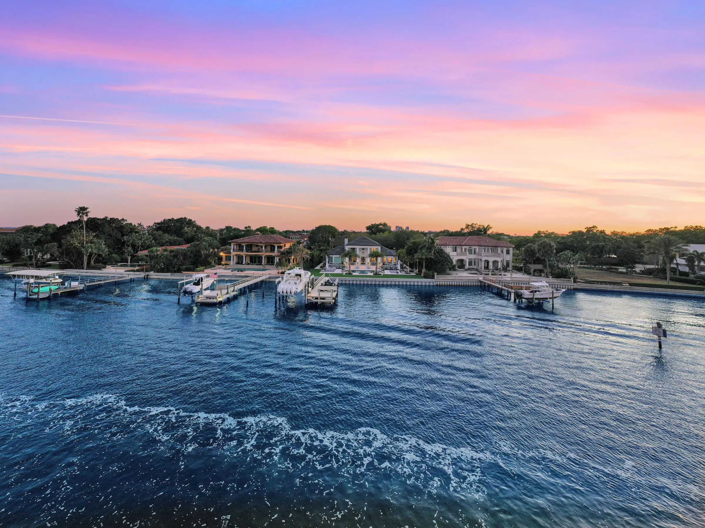 Luxury waterfront homes with private docks and boats at sunset in St Petersburg FL, showcasing premium residential landscape architecture and pool design.