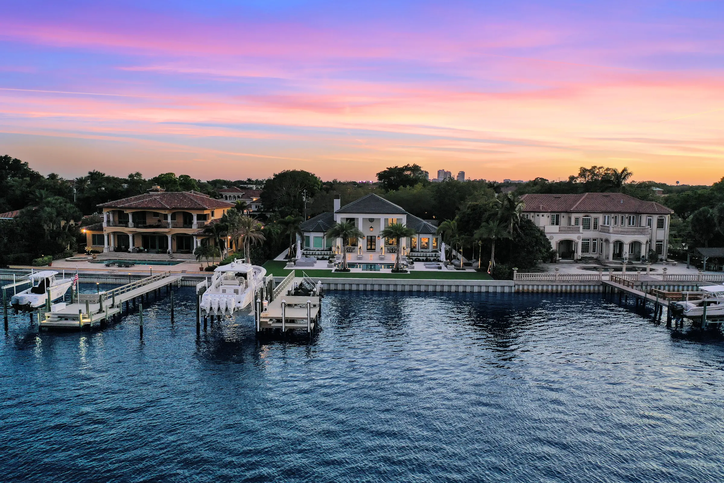 Three luxury waterfront homes with private docks at sunset in St Petersburg, FL, showcasing premium residential architecture and pool design along the intracoastal waterway.