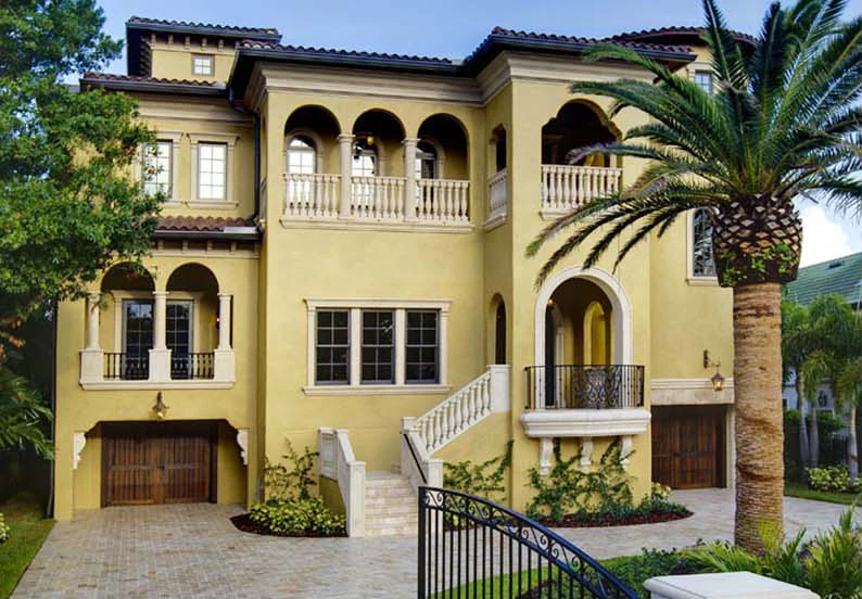 Luxury yellow stucco home with arched balconies, palm tree, and architectural details in St Petersburg residential community.